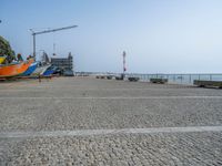 four boats are lined up outside at the beach in front of a crane and water