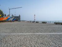 four boats are lined up outside at the beach in front of a crane and water