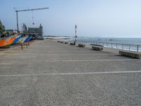 four boats are lined up outside at the beach in front of a crane and water