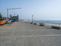 four boats are lined up outside at the beach in front of a crane and water