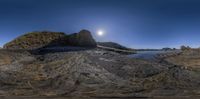 fisheye panoramic view of cliffs and a beach with boats on the shore