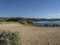 a beach with some rocks and a hill in the background a sign reads one way