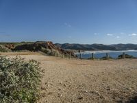 a beach with some rocks and a hill in the background a sign reads one way