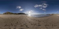 a camera lens view of a beach and sky with tracks in the sand in front of the beach