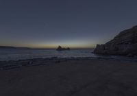 a long exposure photo of rocks along the ocean on a clear night time with the sun rising