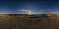 a beach with rocks and the sun in the distance behind it, as if using fisheyes