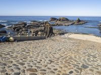 a sea beach area with various rocks, stones, and the ocean in the background