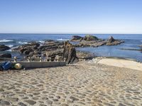 a sea beach area with various rocks, stones, and the ocean in the background