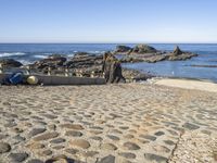 a sea beach area with various rocks, stones, and the ocean in the background