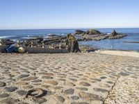 a sea beach area with various rocks, stones, and the ocean in the background