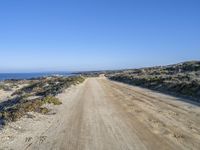 a dirt road on the side of a hill near the water and sea side of the beach