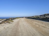 a dirt road on the side of a hill near the water and sea side of the beach