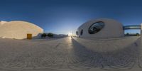 a 360 degree image of a courtyard in the sun with a small building and a big window