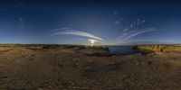 a beach with rocks and the sun in the distance behind it, as if using fisheyes