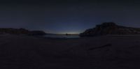 a dark and gloom looking picture of an ocean at night time and moon rise above rocks