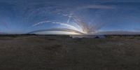 a large long curved cloud is shown from below a road that is surrounded by dirt