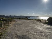 a gravel road leads down the beach towards the ocean, with grassy area and trees