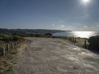 a gravel road leads down the beach towards the ocean, with grassy area and trees