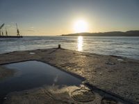 an orange sun shines in a blue puddle on the beach at low tide, and the water has reflectioning