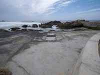 a concrete walkway that leads down to the ocean and has waves crashing on it,