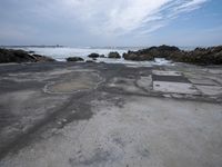 a concrete walkway that leads down to the ocean and has waves crashing on it,