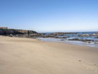 an empty beach is surrounded by rocks and water with footprints in the sand, leaving small footprints in the sand