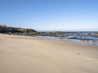 an empty beach is surrounded by rocks and water with footprints in the sand, leaving small footprints in the sand