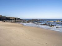 an empty beach is surrounded by rocks and water with footprints in the sand, leaving small footprints in the sand