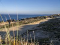 the dirt road leading to the shore is empty and sandy on the other side is an ocean