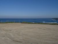 an open field with some very empty beaches and a blue water in the background on a clear day