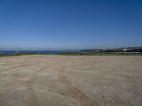 the empty parking lot in front of the beach is a bit empty with a small blue sky and blue water on a sunny day