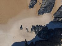 an aerial view of people riding horses through the snow near mountains and sand dunes of the desert