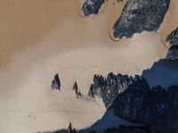 an aerial view of people riding horses through the snow near mountains and sand dunes of the desert