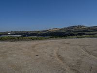 a dirt field with an over head view of hills in the distance and a blue sky above