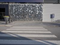 a stoplight next to the side of a building and street with a white striped crosswalk