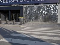 a stoplight next to the side of a building and street with a white striped crosswalk