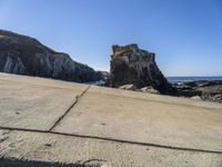 the two rocks are near each other on the shore by the ocean beach near large rocks and the water