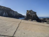 the two rocks are near each other on the shore by the ocean beach near large rocks and the water