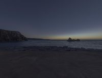 an ocean with rocks under the moonlight light and a crescenty sky in the background