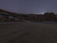 there is a view of an empty mountain at night from the back end of a car on a road