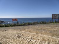 a sign posted at the edge of a stone sidewalk pointing out into the ocean, and another sign indicating no parking, which is right for us