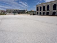 an empty street in front of a building under blue skies with clouds as it passes