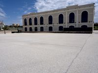 an empty street in front of a building under blue skies with clouds as it passes