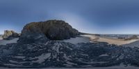 a fish - eye view of some very large rocks on the beach with a small area of sand on the ocean