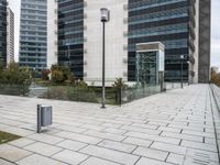 there is a street light by a sidewalk next to tall buildings and grass in front of them