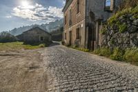 an old country road near a small farm house in a village with mountains in the background