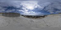 a large cement skate park with a sky background and clouds overhead it's perspective has been edited in half