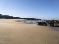 a sandy beach with steps leading up to a hill near an ocean and a hotel