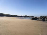 a sandy beach with steps leading up to a hill near an ocean and a hotel