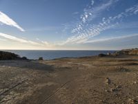 an ocean on the horizon of a desert landscape, with rocky shoreline on right side